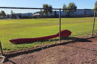 A 15-foot red spoon lying behind a fence in Phoenix, April 3, 2023.