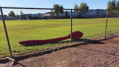 A 15-foot red spoon lying behind a fence in Phoenix, April 3, 2023.