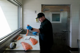 Luis Alvarenga, executive chef at Scoma's, cleans a farm-raised salmon in San Francisco, March 20, 2023.