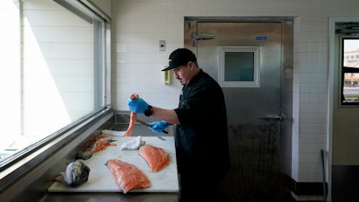 Luis Alvarenga, executive chef at Scoma's, cleans a farm-raised salmon in San Francisco, March 20, 2023.