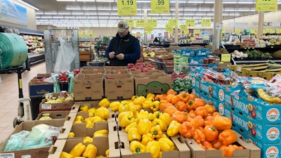 A man looks at his mobile phone while shopping at a grocery store in Buffalo Grove, Ill., March 19, 2023.