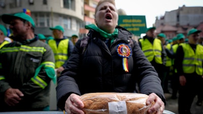 A woman holds a loaf of bread during a farmers' protest in front of the Representative Office of the European Commission, Bucharest, Romania, April 7, 2023.