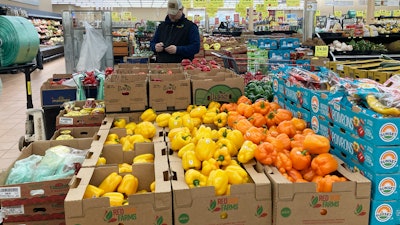 A man looks at his mobile phone while shopping at a grocery store in Buffalo Grove, Ill., Sunday, March 19, 2023. On Wednesday, the Labor Department reports on U.S. consumer prices for March.