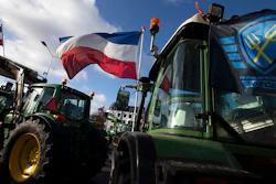 The Farmers Defense Force flag, right, and Dutch flags, fly in the wind on an intersection blocked by tractors in The Hague, Netherlands, Feb. 19, 2020.