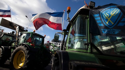 The Farmers Defense Force flag, right, and Dutch flags, fly in the wind on an intersection blocked by tractors in The Hague, Netherlands, Feb. 19, 2020.