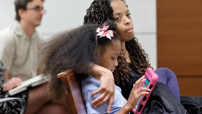Philana Holmes and her daughter Olivia Caraballo, 7 listen to the final witness in their case at the Broward County Courthouse in Fort Lauderdale on Wednesday May 10, 2023.