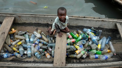 A child sits inside a canoe with empty plastic bottles he collected to sell for recycling in the floating slum of Makoko, Lagos, Nigeria, Nov. 8, 2022.