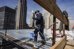 Construction workers install roofing on a high rise in Manhattan's financial district on Tuesday, April 11, 2023, in New York. On Friday, the U.S. government issues the April jobs report.