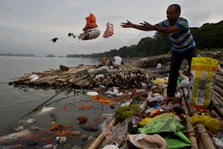 A Hindu devotee throws flowers and plastic bags into the river Brahmaputra in Gauhati, India, Oct. 9, 2019.