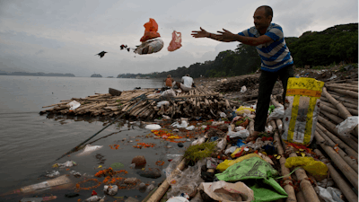 A Hindu devotee throws flowers and plastic bags into the river Brahmaputra in Gauhati, India, Oct. 9, 2019.