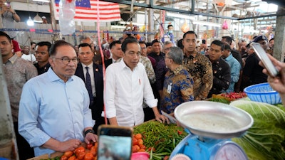 Indonesian President Joko Widodo, center, with Malaysian Prime Minister Anwar Ibrahim at a wet market in Kuala Lumpur, June 8, 2023.