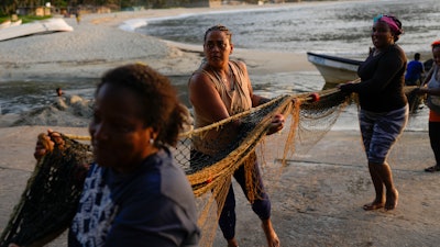 Greyla Aguilera and her coworkers carry a net on the coast of Chuao, Venezuela, June 8, 2023.