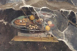 A fresco, depicting a table with food, on the wall of an ancient Pompeian house.