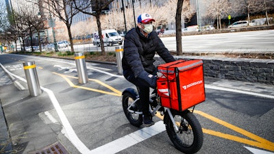 A delivery worker rides his bicycle along a path on the West Side Highway in New York, March 16, 2020.