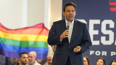 Protesters unfold and raise a rainbow flag behind Republican presidential candidate Florida Gov. Ron DeSantis during a campaign event, Tega Cay, S.C., July 17, 2023.