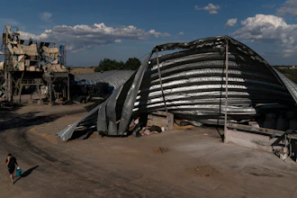 An employee walks near mangled warehouses at a grain facility in Pavlivka, Ukraine, July 22, 2023.