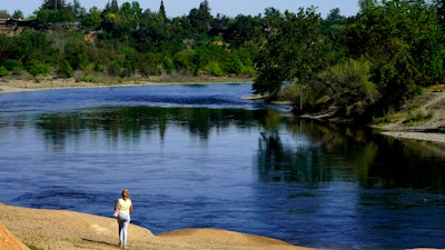 A woman walks along the banks of the American River, Rancho Cordova, Calif., April 8, 2022.