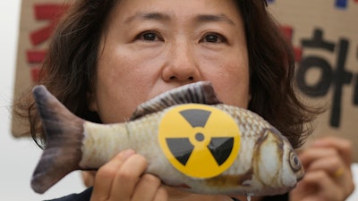 A woman holds a mock fish during a rally in Seoul, Aug. 24, 2023.