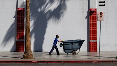 A maintenance worker pushes a cart in Las Vegas, Friday, Aug. 25, 2023.