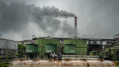 Workers seal the lid of an ethanol tank at the Bajaj Hindustan Sugar factory, Meerut, India, Aug. 23, 2023.