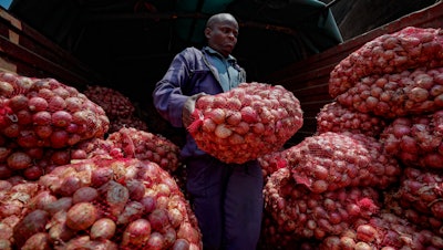 Timothy Kinyua unloads sacks of onions at a market in Nairobi, Kenya, Sept. 12, 2023.