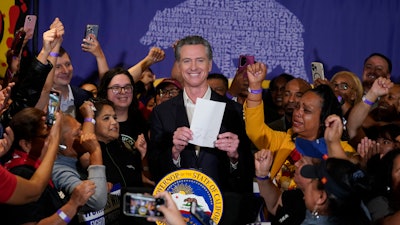 California Gov. Gavin Newsom signs the fast food bill surrounded by fast food workers at the SEIU Local 721 in Los Angeles, on Thursday, Sept. 28, 2023.
