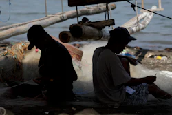 Fishermen work on nets in a coastal village, Cavite province, Philippines, May 7, 2020.
