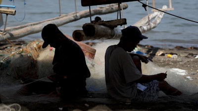 Fishermen work on nets in a coastal village, Cavite province, Philippines, May 7, 2020.
