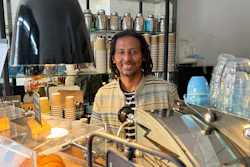 Anteneh Mulu, 46, poses behind the counter after serving a customer at his coffee shop, The Ethiopian Coffee Company, in central London on Thursday, Aug. 31, 2023. Mulu and his business partner Polly Hamilton, 79, opened their shop in 2013. The London-based International Coffee Organization has declared this Sunday, Oct. 1, as International Coffee Day.