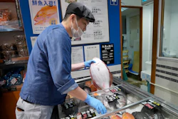 A staff member holds a flounder from Fukushima at Sakana Bacca, Tokyo, Oct. 31, 2023.