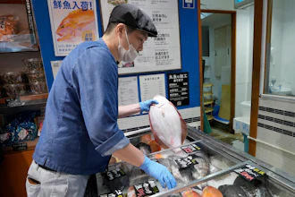 A staff member holds a flounder from Fukushima at Sakana Bacca, Tokyo, Oct. 31, 2023.