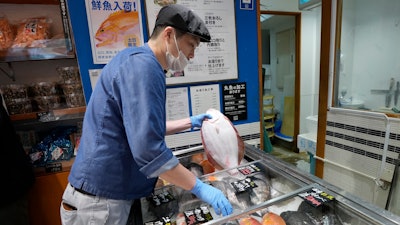 A staff member holds a flounder from Fukushima at Sakana Bacca, Tokyo, Oct. 31, 2023.
