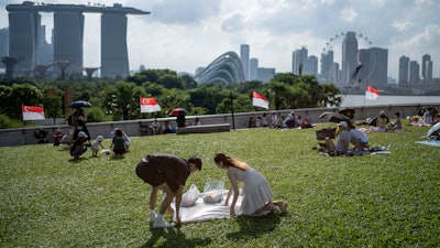 A couple spreads a blanket for a picnic on the grassy roof of the Marina Barrage pumping station, Singapore, July 22, 2023.