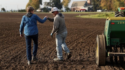 Gayle Goschie fist bumps Eloy Luevanos after setting up a harrow to be pulled behind a tractor and grain hopper in preparation for planting winter barley at Goschie Farms in Mount Angel, Ore., Tuesday, Oct. 31, 2023.