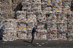 A GreenNet recycling plant employee cleans the ground next to piles of disposable plastic ready for export, in Atarot industrial zone, north of Jerusalem, Jan. 25, 2023.