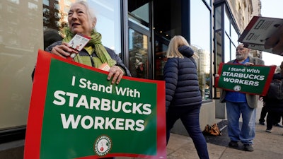 Arlene Geiger, left, holds a sign supporting Starbucks workers outside a Starbucks on New York's Upper West Side, Nov. 16, 2023.