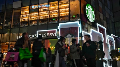 Shoppers walk by a Starbucks cafe at an outdoor shopping mall in Beijing, Dec. 23, 2023.