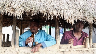Benson Muhereza drinks tonto at a bar, Majengo village, Uganda, Dec. 10, 2023.