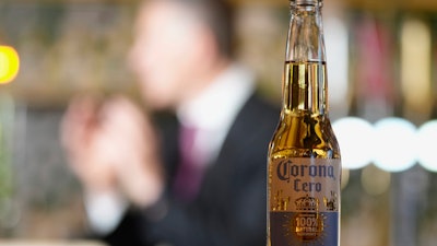 A bottle of Corona Cero beer with Anheuser-Busch InBev CEO Michel Doukeris speaking in the background, London, Jan. 12, 2024.