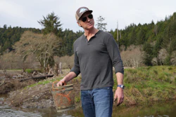 California Gov. Gavin Newsom holds fish trap while touring a salmon restoration project in Redwoods National Park, Calif., Jan. 29, 2024.