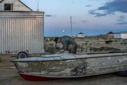 A man repairs an old boat along the dried-up Aral Sea, Tastubek, Kazakhstan, July 2, 2023.
