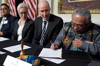 Chair Gerry Lewis of the Yakama Nation, right, signs a document during a signing ceremony in Washington, Feb. 23, 2024.