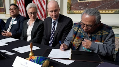 Chair Gerry Lewis of the Yakama Nation, right, signs a document during a signing ceremony in Washington, Feb. 23, 2024.