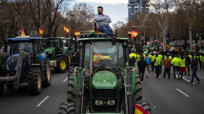 A farmer sits atop a tractor during a protest outside the European Parliament offices in Madrid, Feb. 26, 2024.