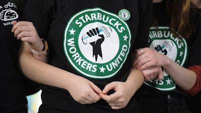 Starbucks employees and supporters link arms during a union election watch party, Buffalo, N.Y., Dec. 9, 2021.