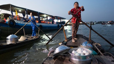 Nguyen Thi Thuy and another bun vendor alongside a passing tourist boat, Can Tho, Vietnam, Jan. 17, 2024.