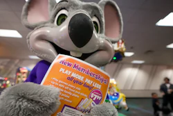 An employee dressed as Chuck E. Cheese holds a flyer advertising new memberships at a location in San Diego, March 13, 2024.