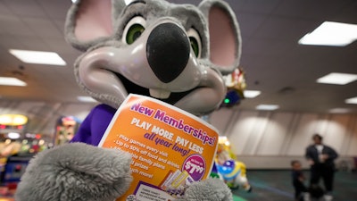An employee dressed as Chuck E. Cheese holds a flyer advertising new memberships at a location in San Diego, March 13, 2024.
