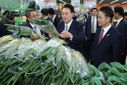 South Korean President Yoon Suk Yeol, center, checks the price of green onions at Nonghyup Hanaro Mart, Seoul, March 18, 2024.