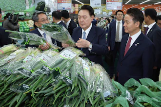 South Korean President Yoon Suk Yeol, center, checks the price of green onions at Nonghyup Hanaro Mart, Seoul, March 18, 2024.